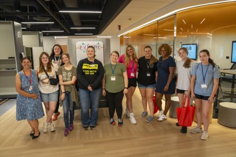 a group of students stand smiling inside the Health Professions Hub simulation center