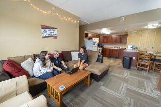 Three roommates laughing, sitting on a couch.