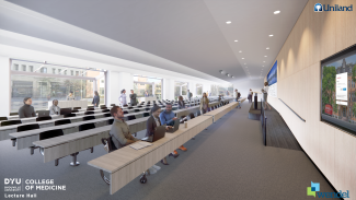 Large room with long rows of tiered seating facing large projection screens