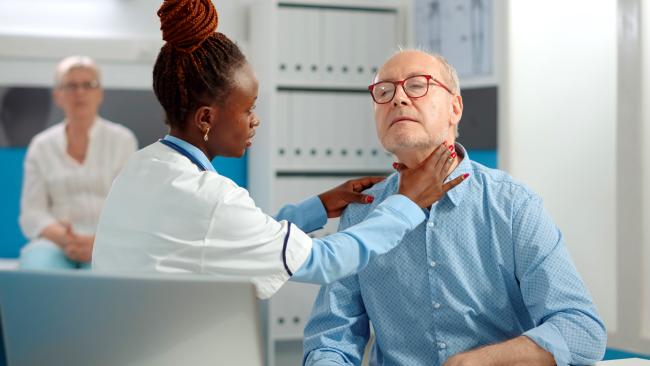 senior patient having his throat checked by doctor at hospital