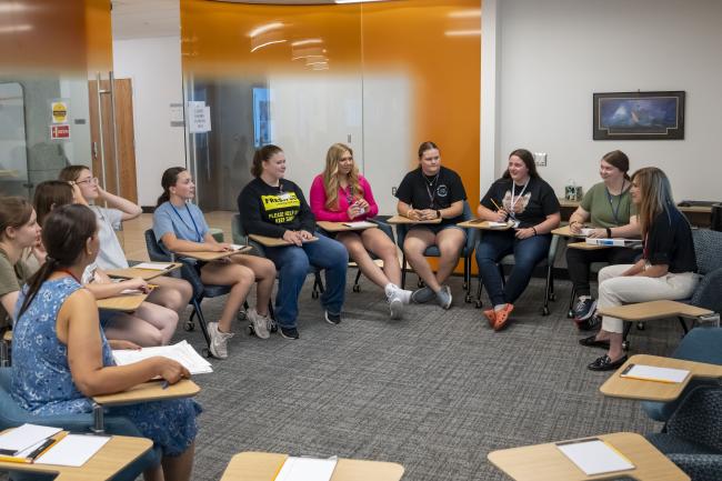 students having a discussion with a professor seated in a circle