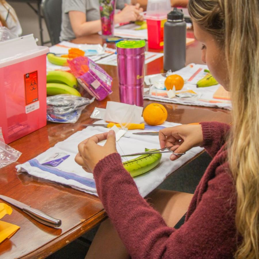 Female student practicing sutures on a banana