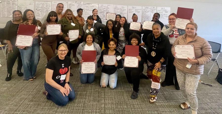 a group of community health workers posing for a photo with certificates after training at D'Youville University