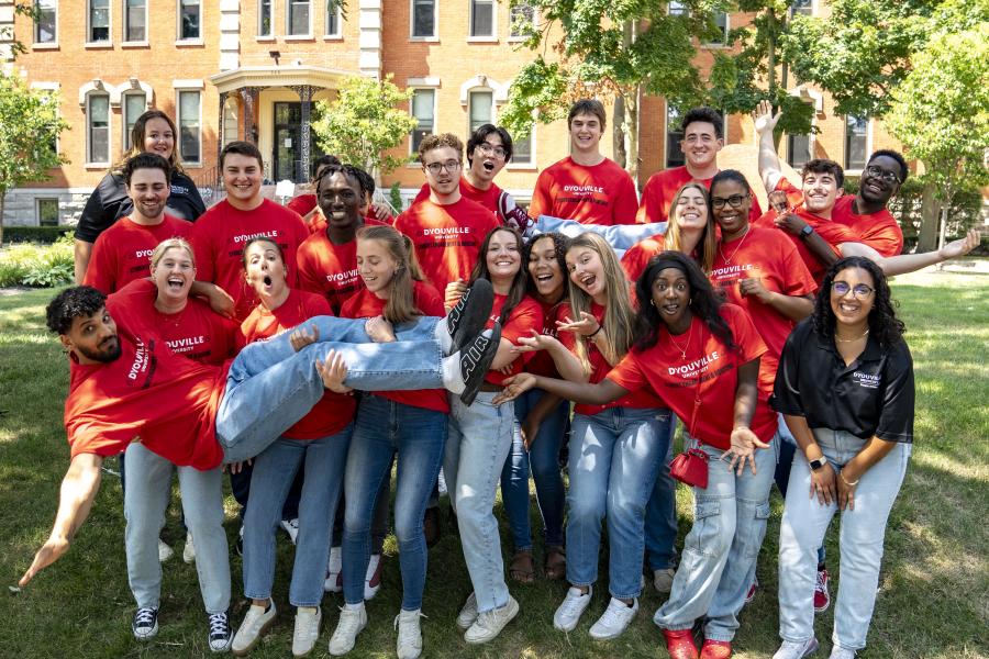 A group of students gathered together for a group picture. They are making funny faces and one student is being held by a few others in the front.