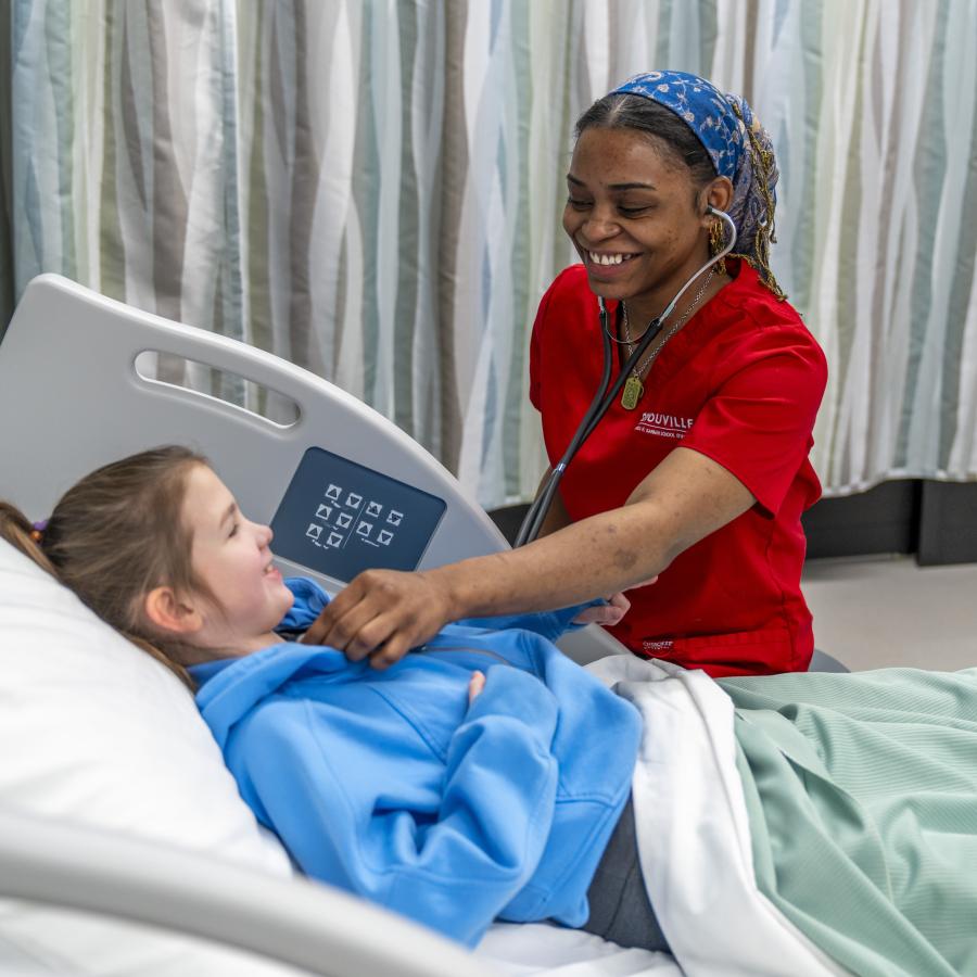 D'Youville University nursing student takes the temperature of a actor patient in a simulation lab