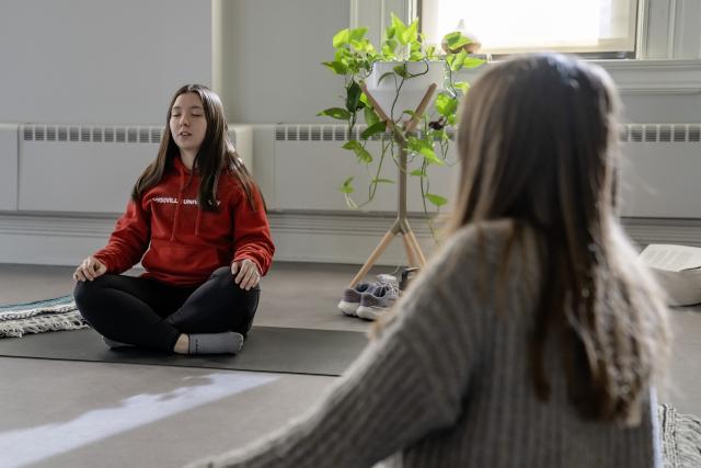 Woman in workout clothes sits cross-legged on the floor practicing meditation